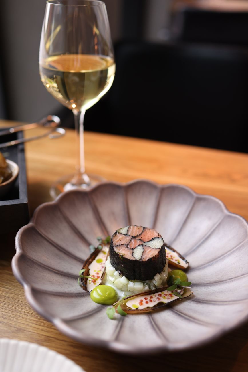 Image illustrating: A refined plant-forward tasting menu dish in a fine-dining restaurant setting (editorial)