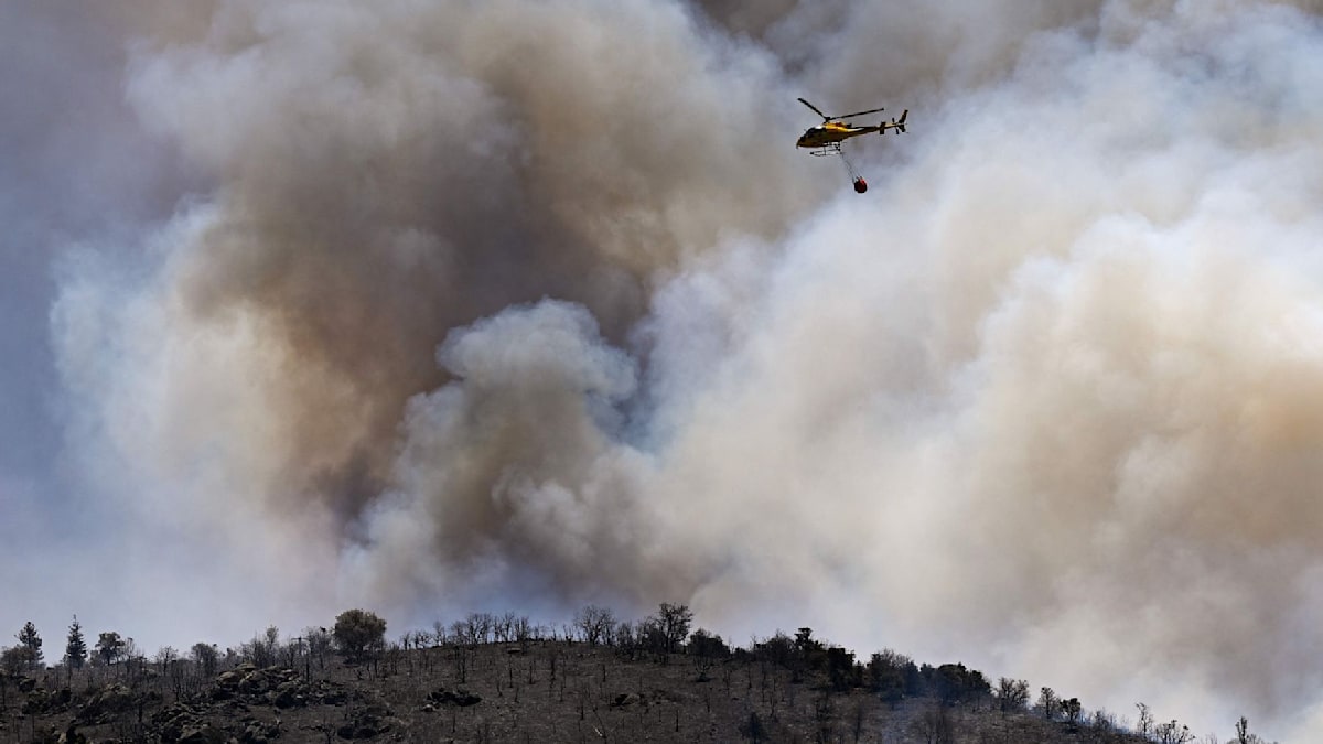 Firefighters and smoke near a Mediterranean wildfire evacuation zone in southern France