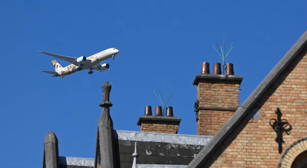 A passenger aircraft flying low over residential Brussels rooftops near the Brussels Airport flight path
